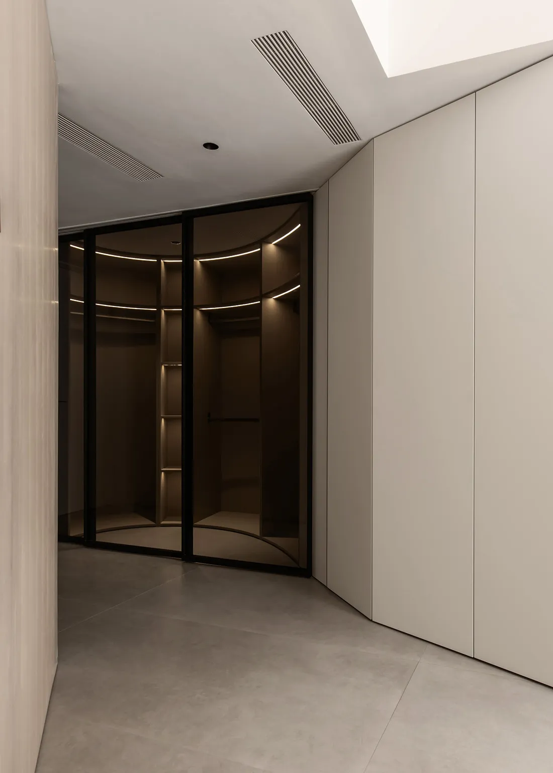 Modern modular closet with glass panels and lighting inside.