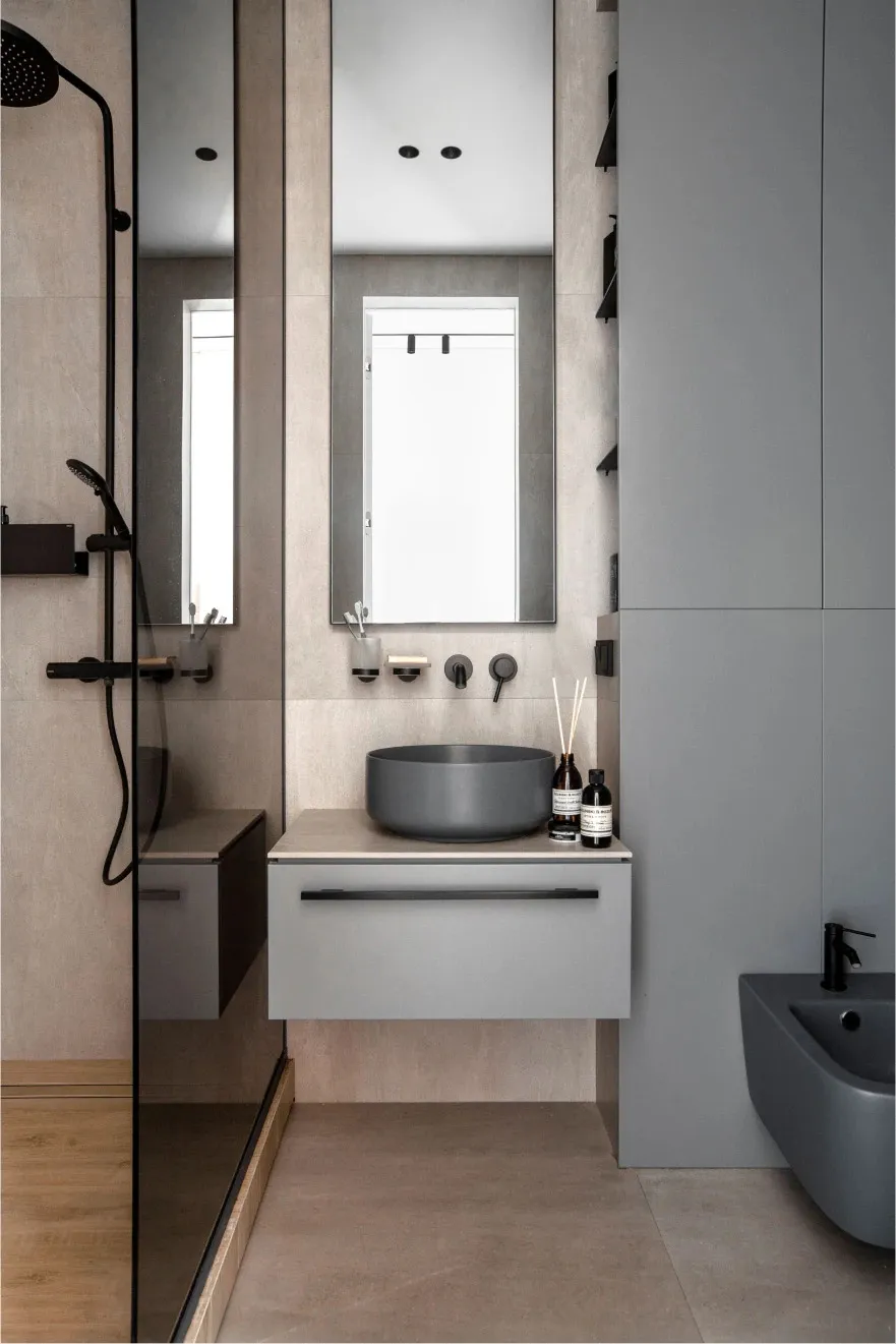 Modern minimalist bathroom with concrete walls and floor, glass shower enclosure, and a floating vanity with a round sink.
