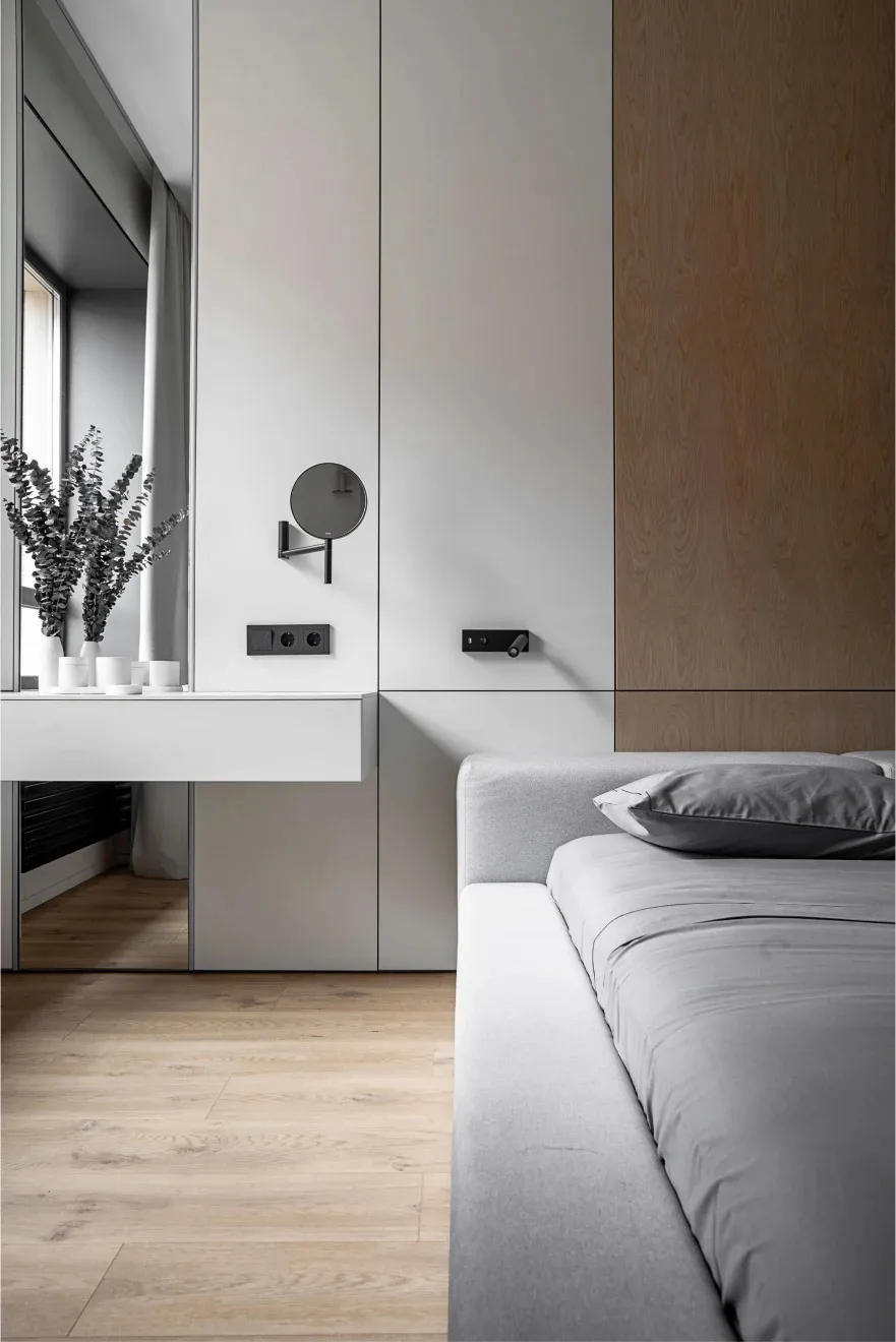 Modern, minimalist bedroom featuring grey furniture and wooden flooring.
