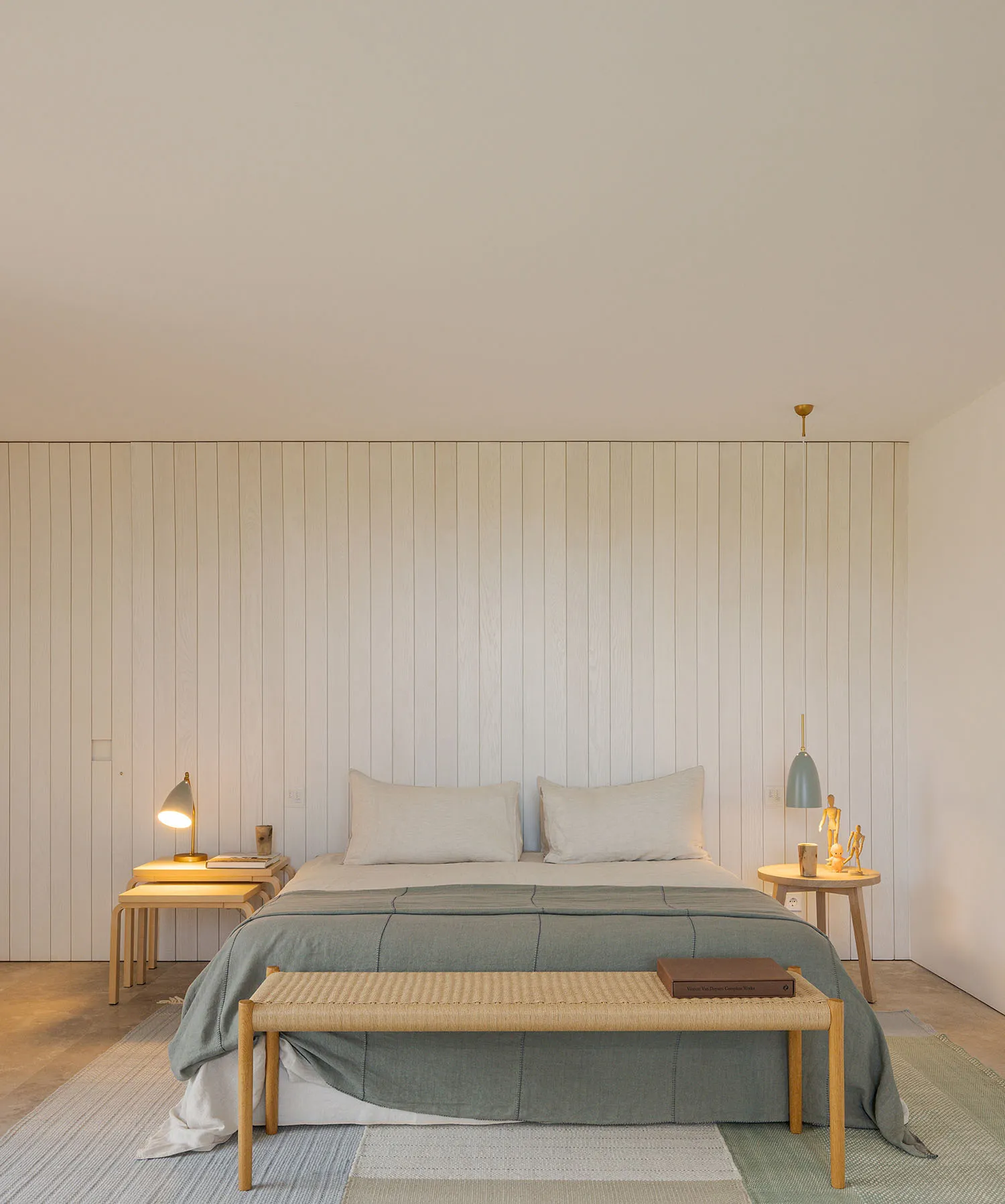 A minimalist bedroom with white walls, light wood furniture, and minimal decorative elements.