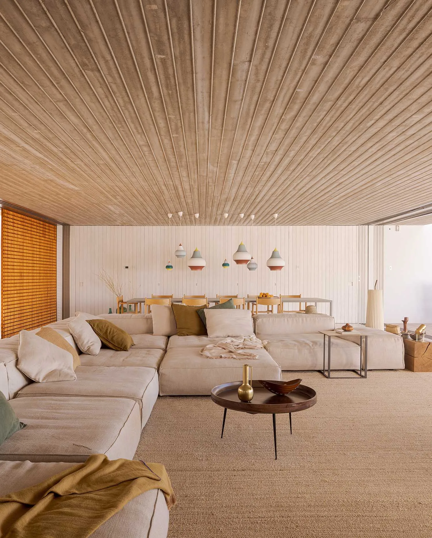 Minimalist living room with concrete walls and ceiling, featuring a large sectional sofa and a coffee table.