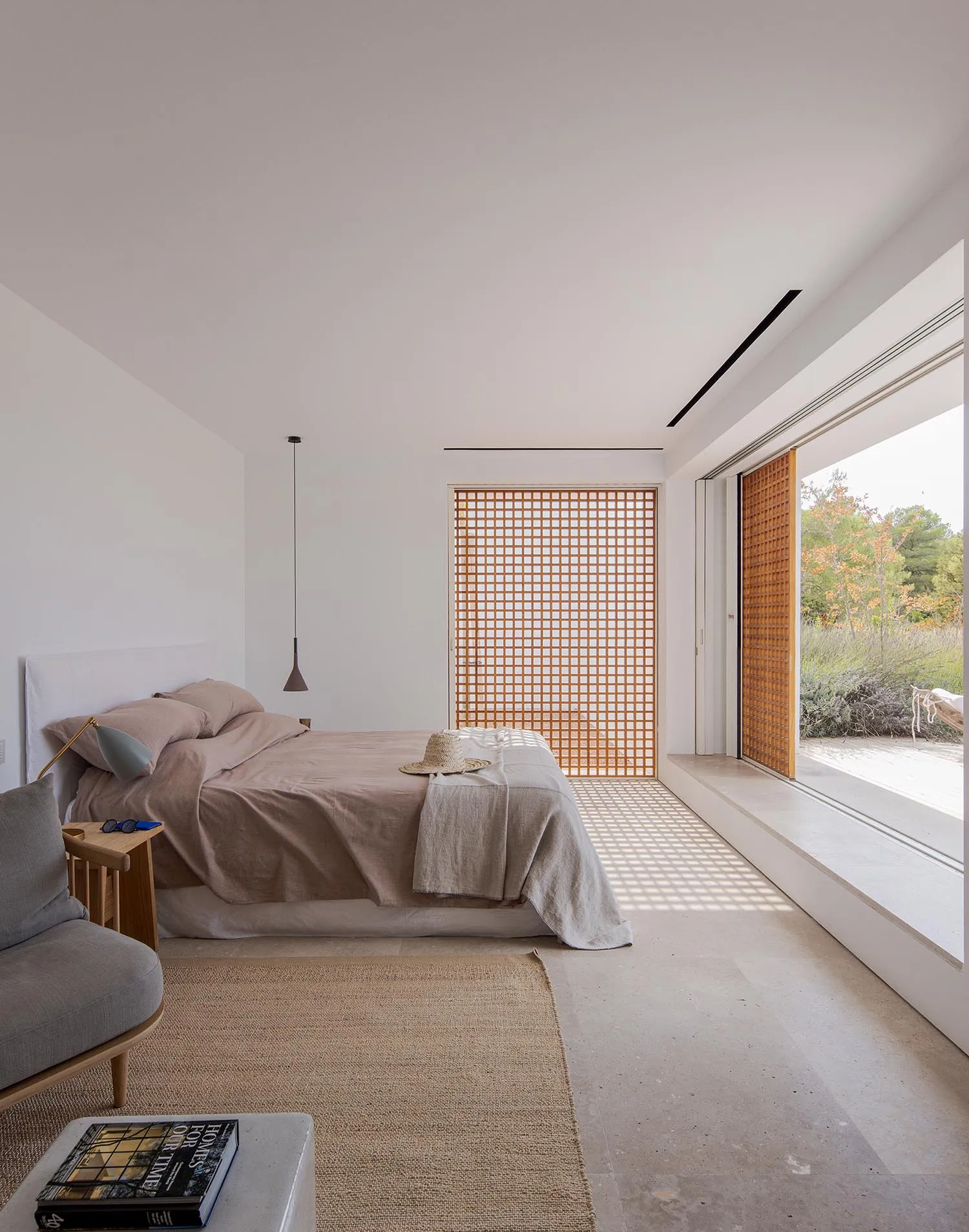 Bedroom with minimalist design, concrete flooring, wooden accents, and fabric bedding.