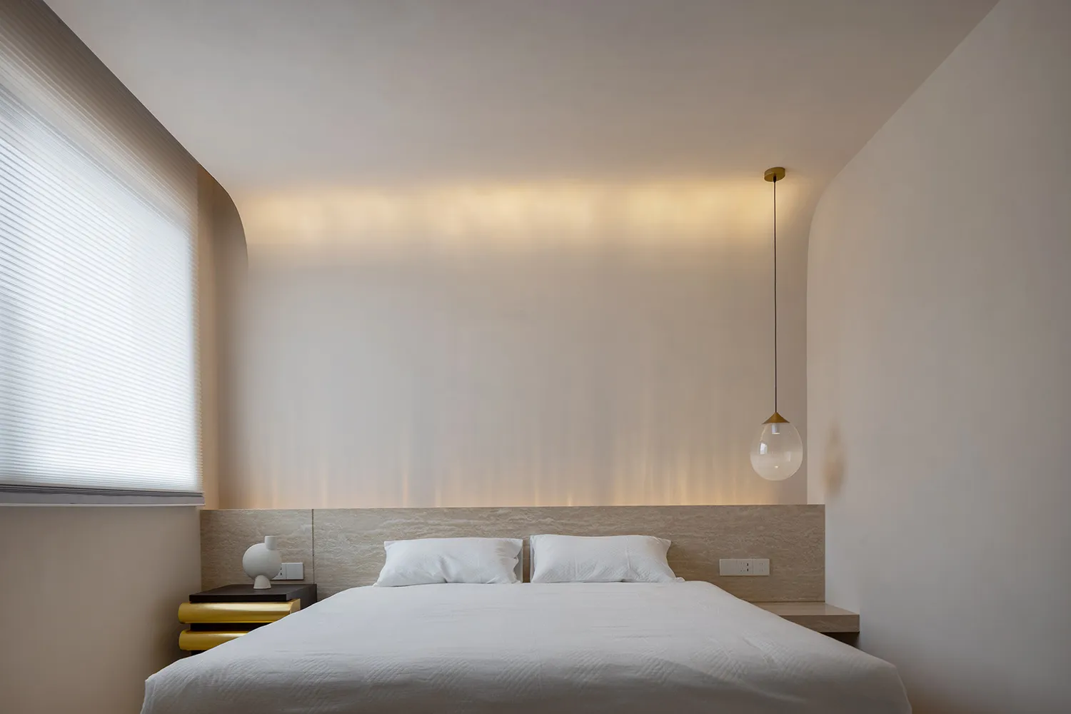 Modern minimalist bedroom featuring a wooden headboard and white blinds.