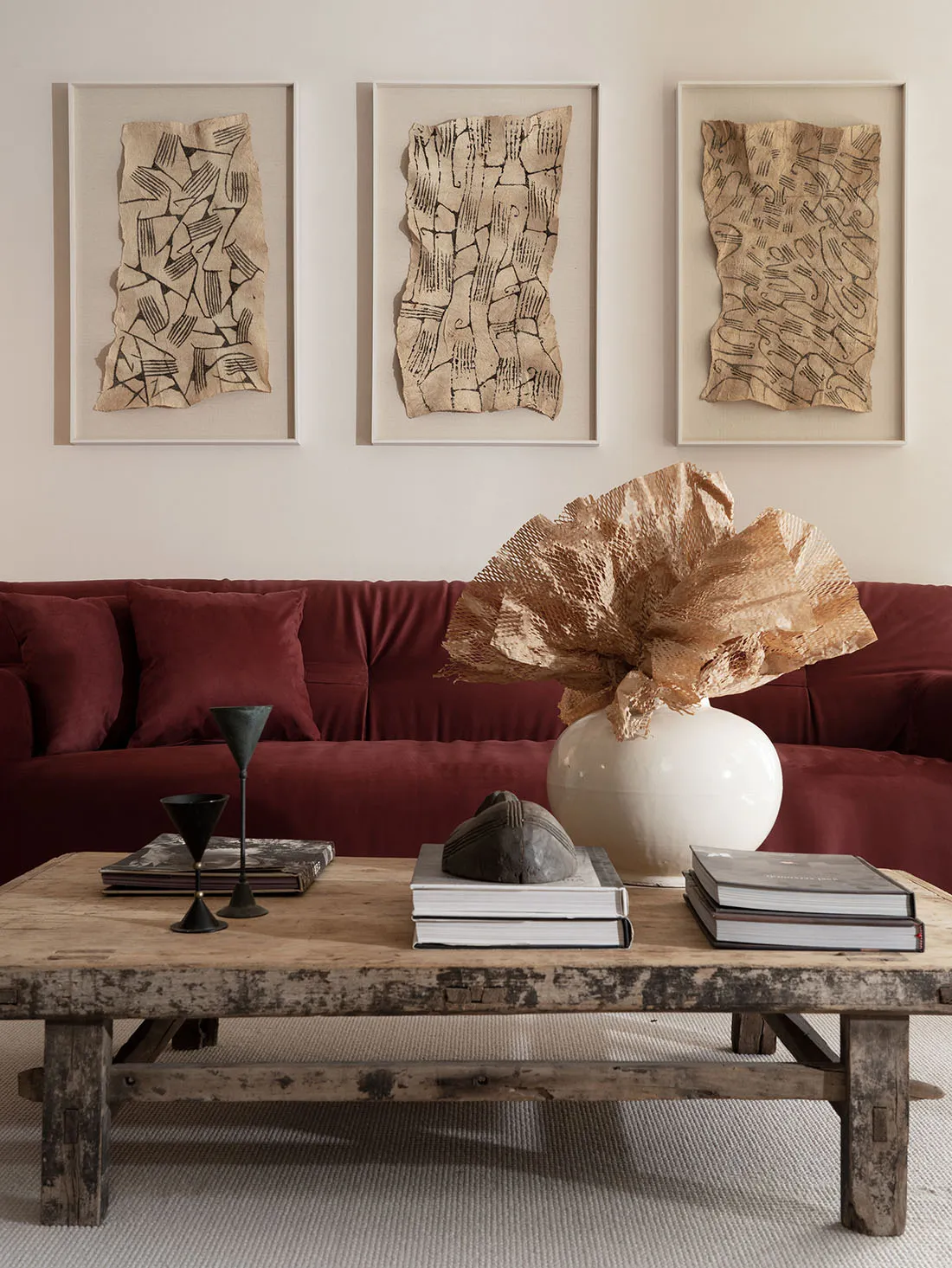 A modern industrial living room with a wooden table, metal sculptures, and paper art on the wall.