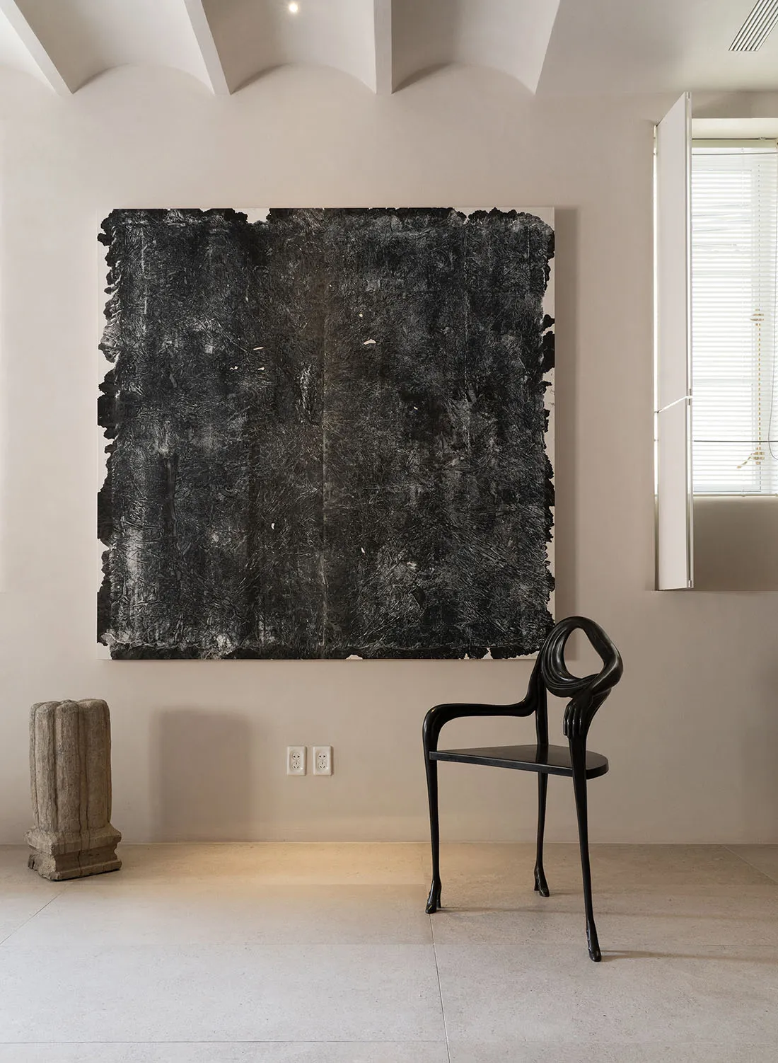 A large, black acrylic painting with an expressionistic texture hanging on a wall.
