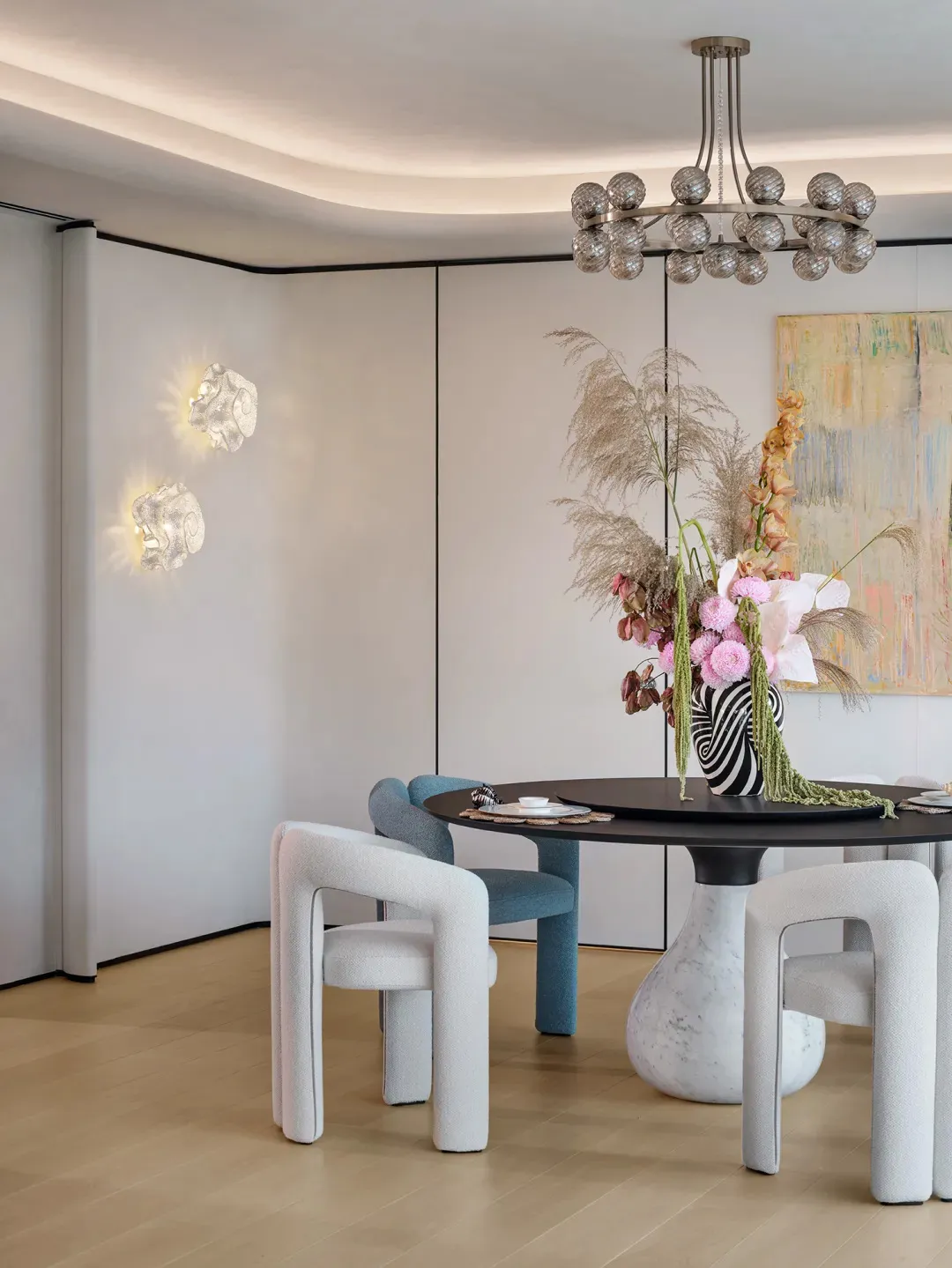 A modern dining room with a round table, marble chairs, and decorative flower arrangement on the table.