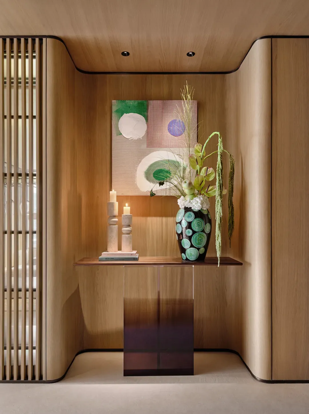 Modern entryway featuring wood paneling with decorative elements such as candles, a vase with flowers, and abstract art.