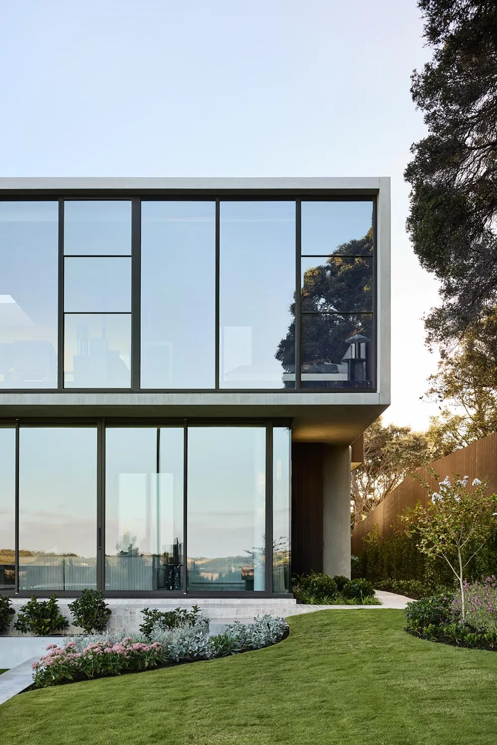 Modern house exterior featuring large glass windows and landscaped garden.
