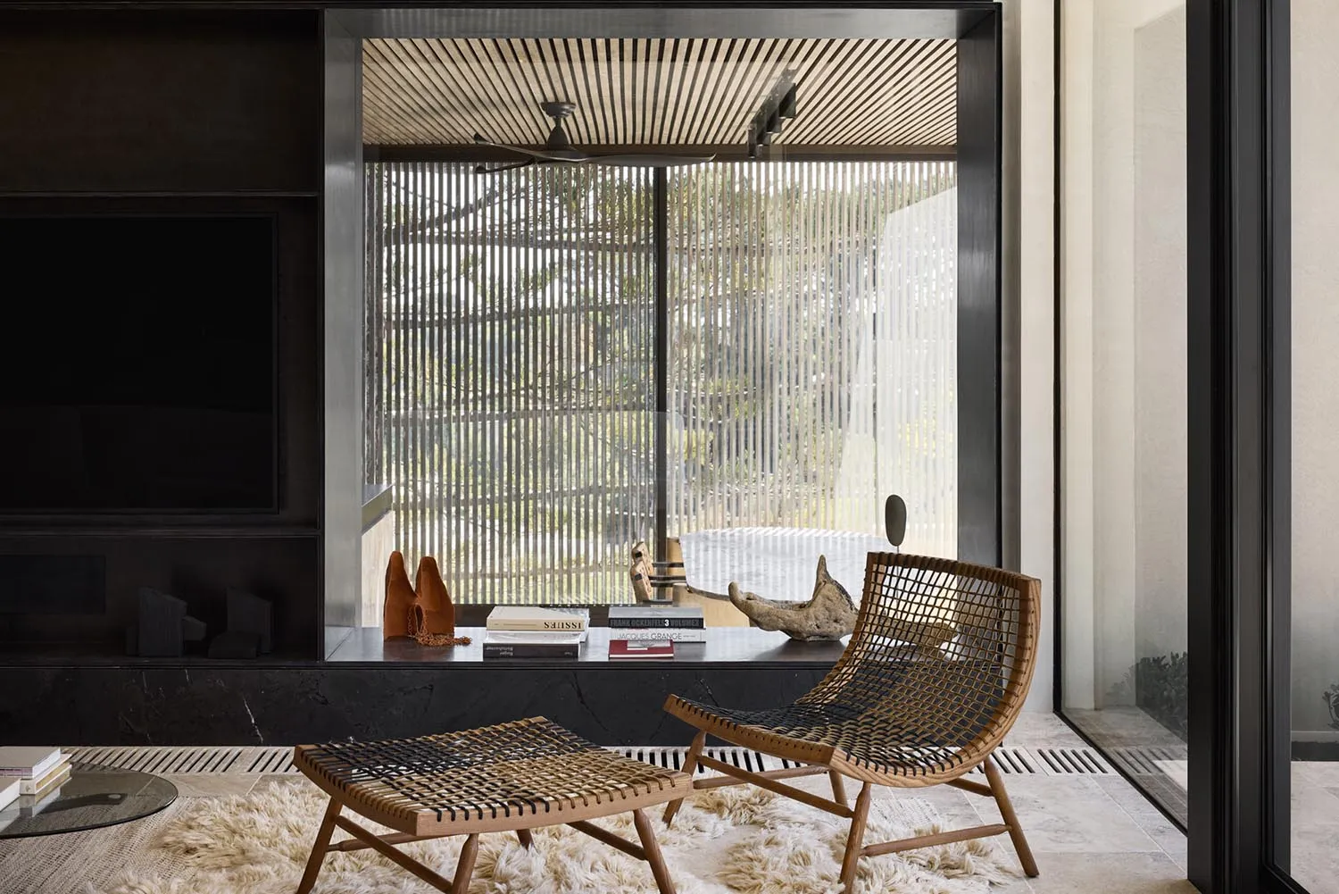 A modern living room with a wooden chair and ottoman, glass shelves, and a leather footstool.