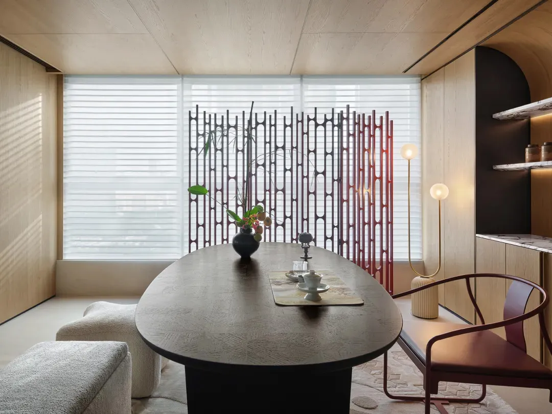 A modern minimalist dining room with wooden furniture, a vase of flowers, and floor lamps.