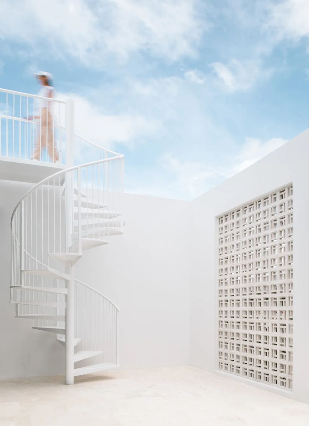 白色建築空間，設有螺旋樓梯，上層有人行走。