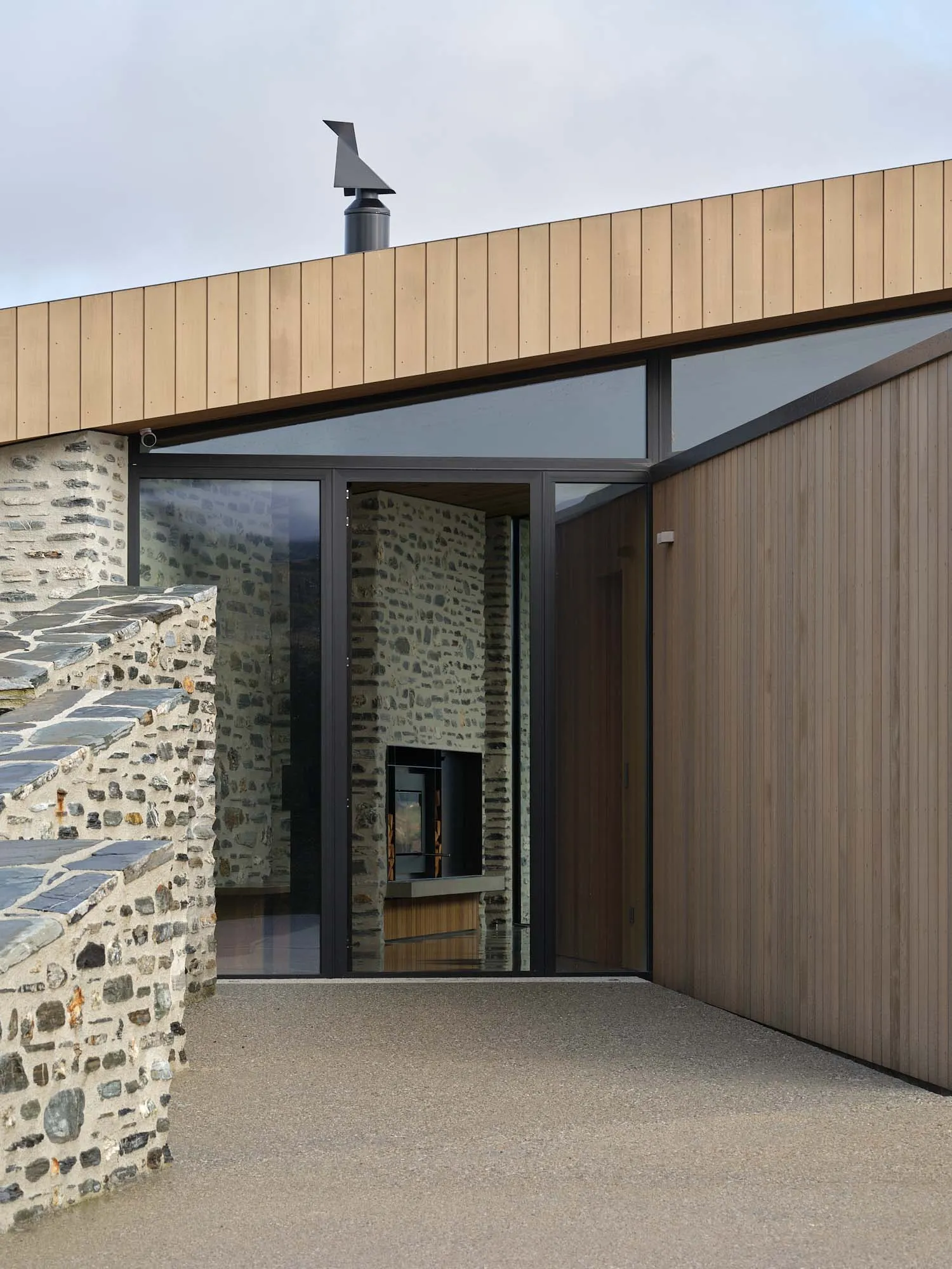 Facade of a minimalist architectural exterior featuring stone and wooden materials.
