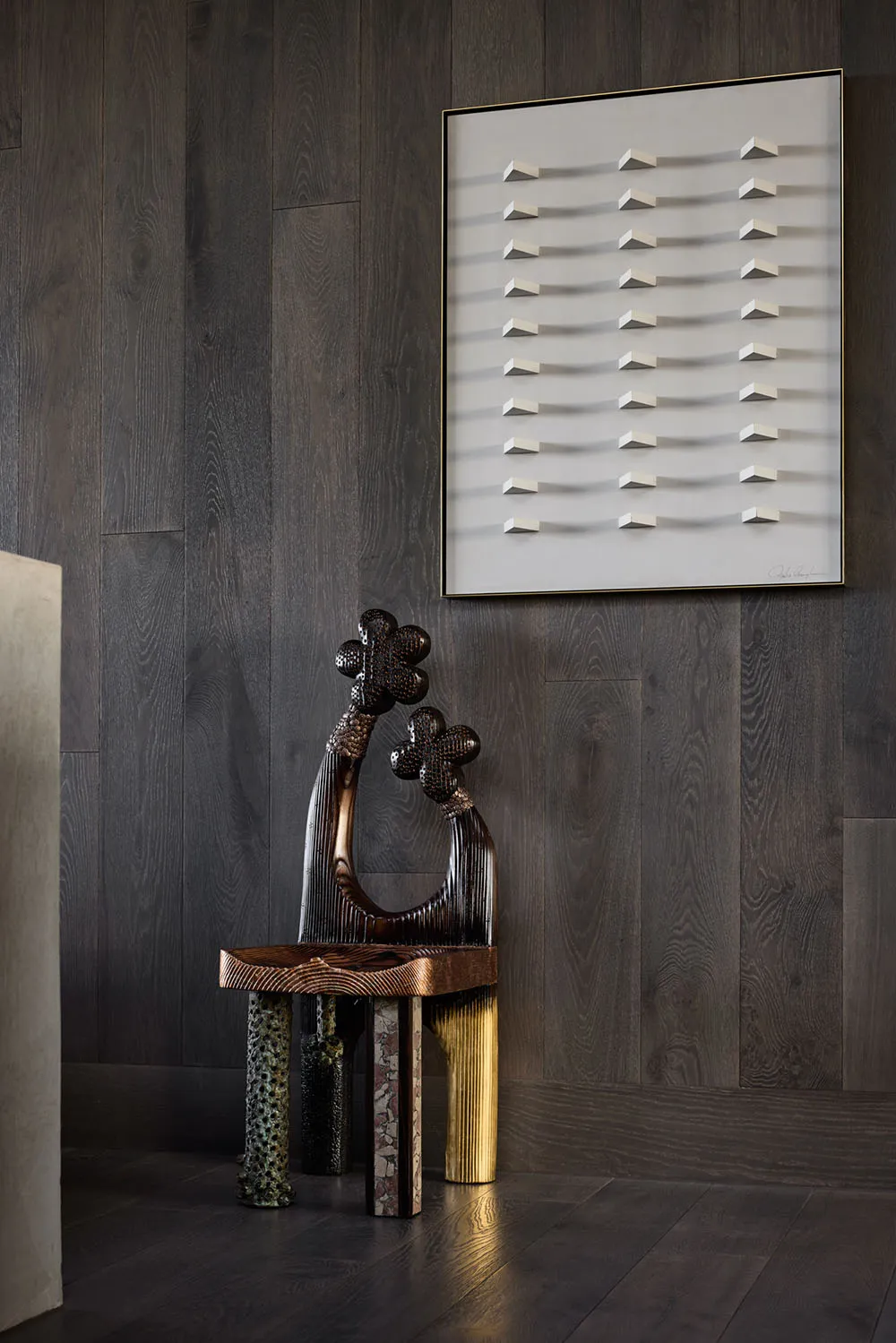 A modern artwork featuring metallic elements against a wooden wall background.