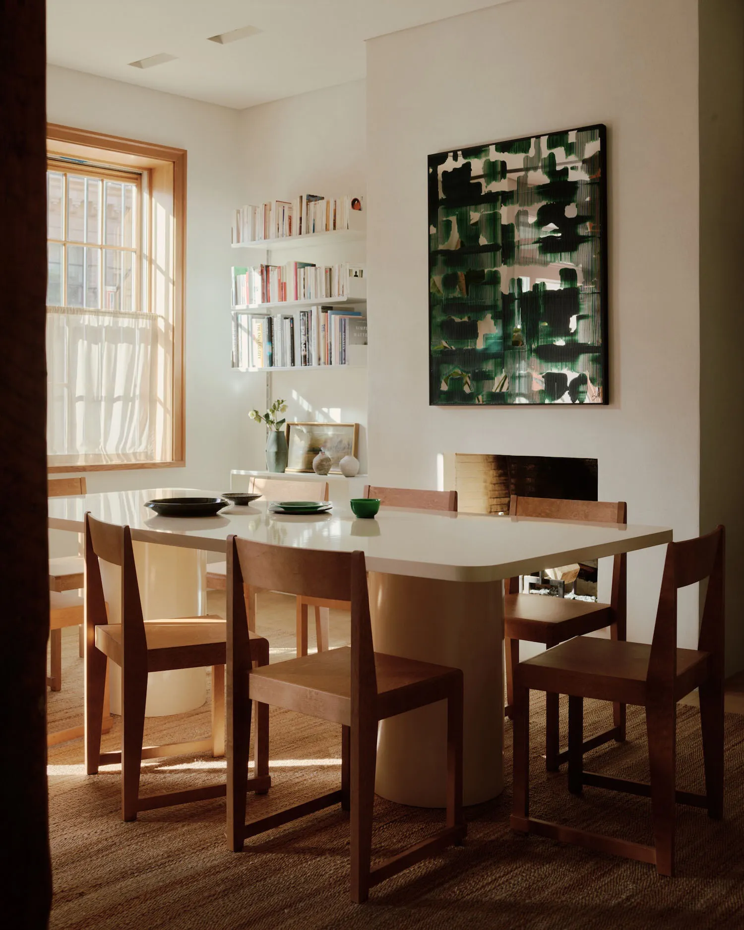 Modern dining room featuring a wooden table and chairs, with a white tabletop and green accents.