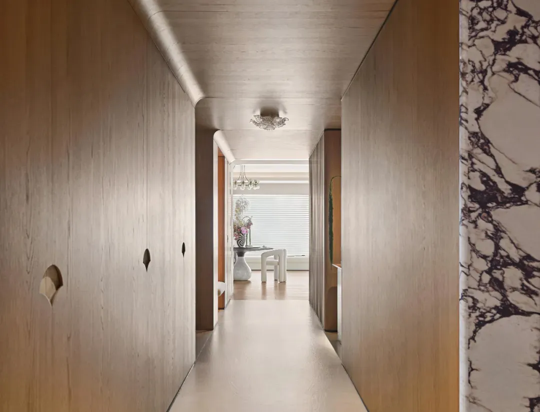 A modern interior hallway with wooden panels and a marble wall