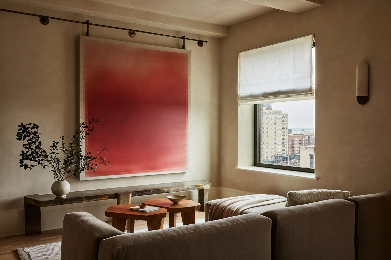 Modern living room featuring neutral-colored sofas, marble top coffee tables, and a large abstract red painting