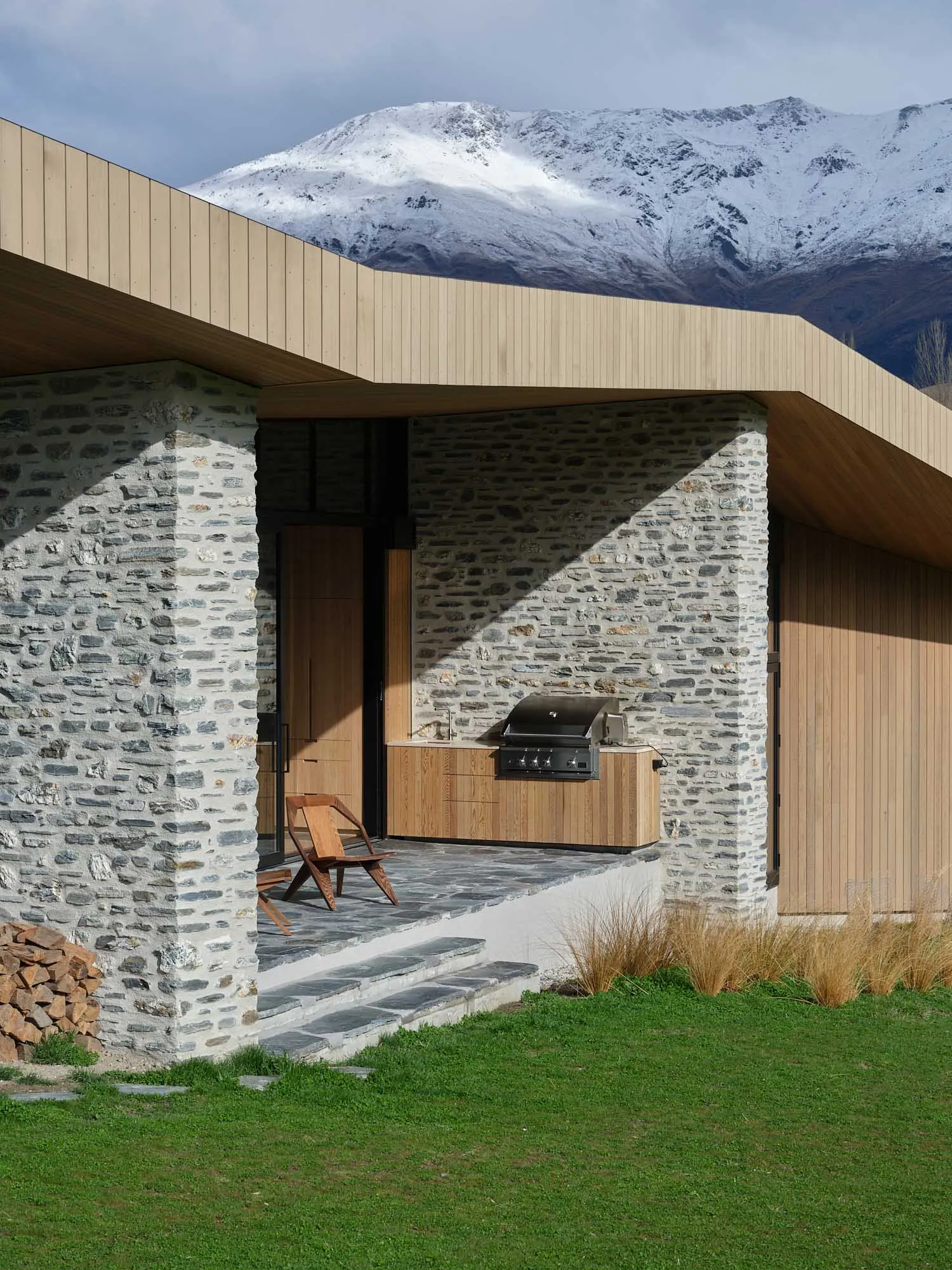 Modern residential exterior with stone, wood, and concrete materials