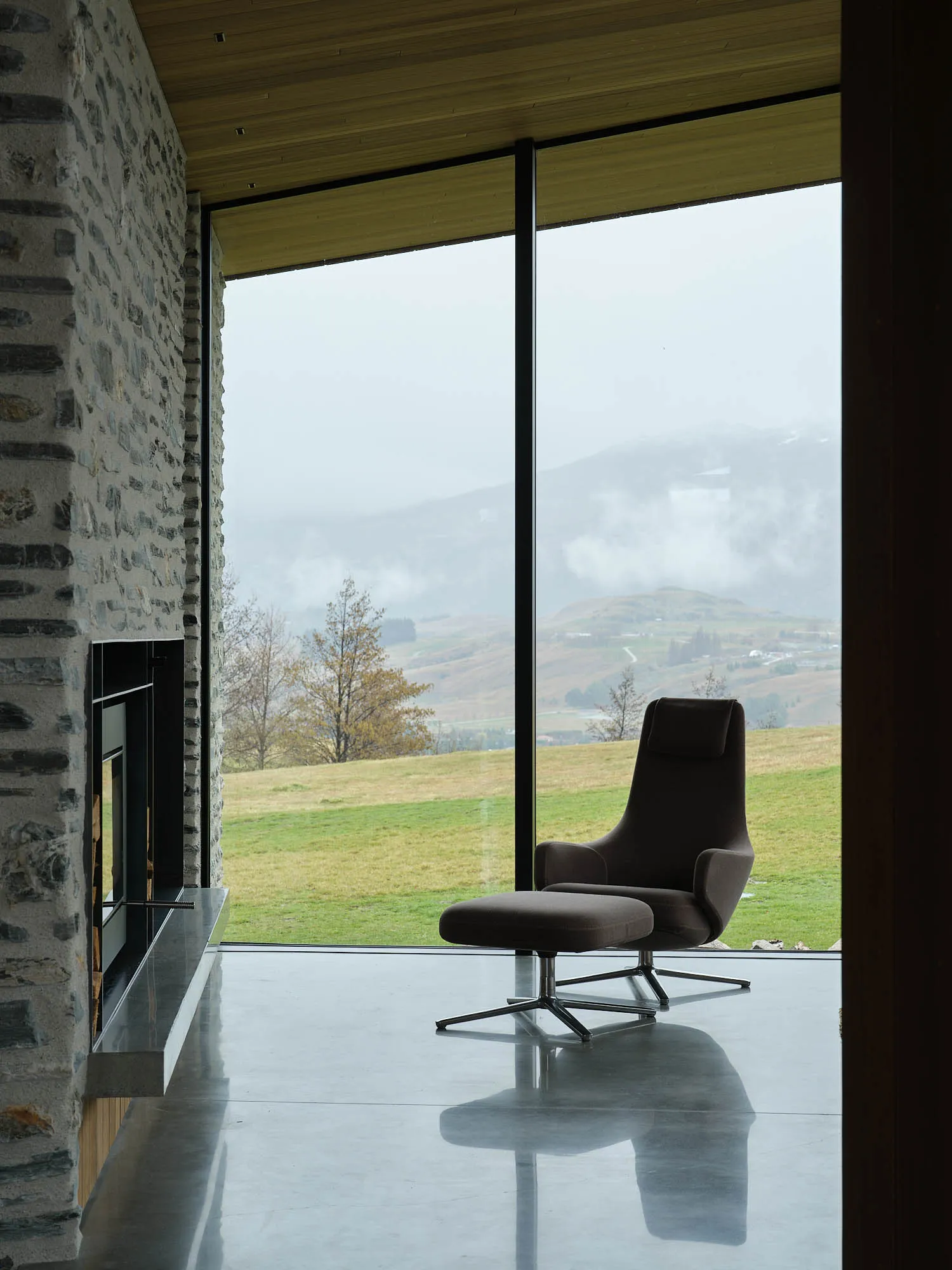 A modern residential space featuring minimalist furniture, a fireplace, and a large window with a view of the mountains.