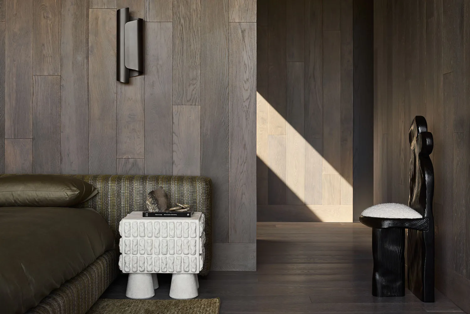 A modern bedroom with dark wooden walls and flooring, featuring a contemporary bed and minimalist furniture.