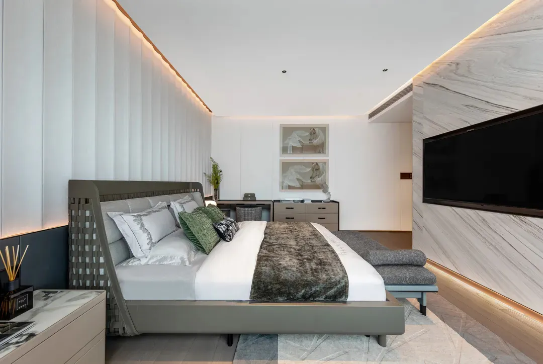 A minimalist bedroom with a modern design, featuring a large bed, white walls, and a marble-like accent wall.