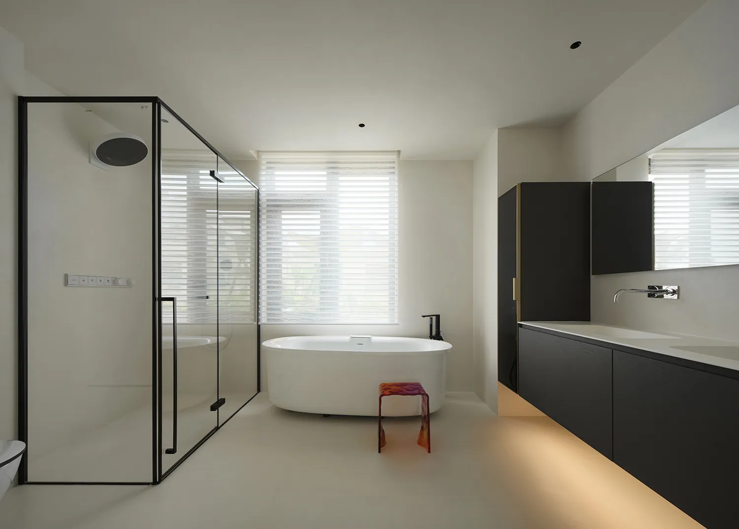 A modern residential bathroom featuring a glass shower enclosure, a freestanding bathtub, and sleek black cabinetry with unde
