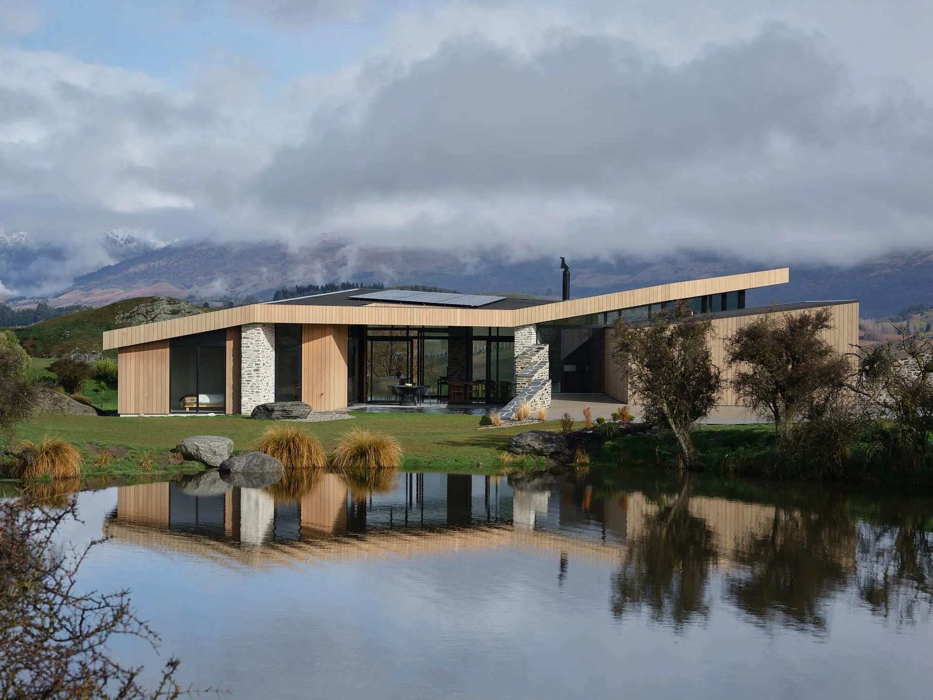 A modern house with a wooden exterior situated in a rural area.