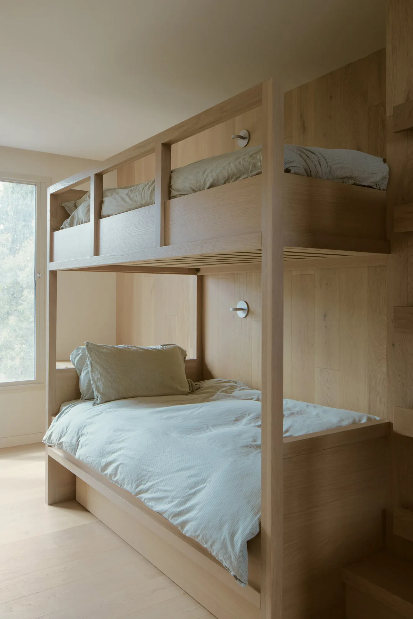 A modern wooden bunk bed with a light blue mattress and pillows.