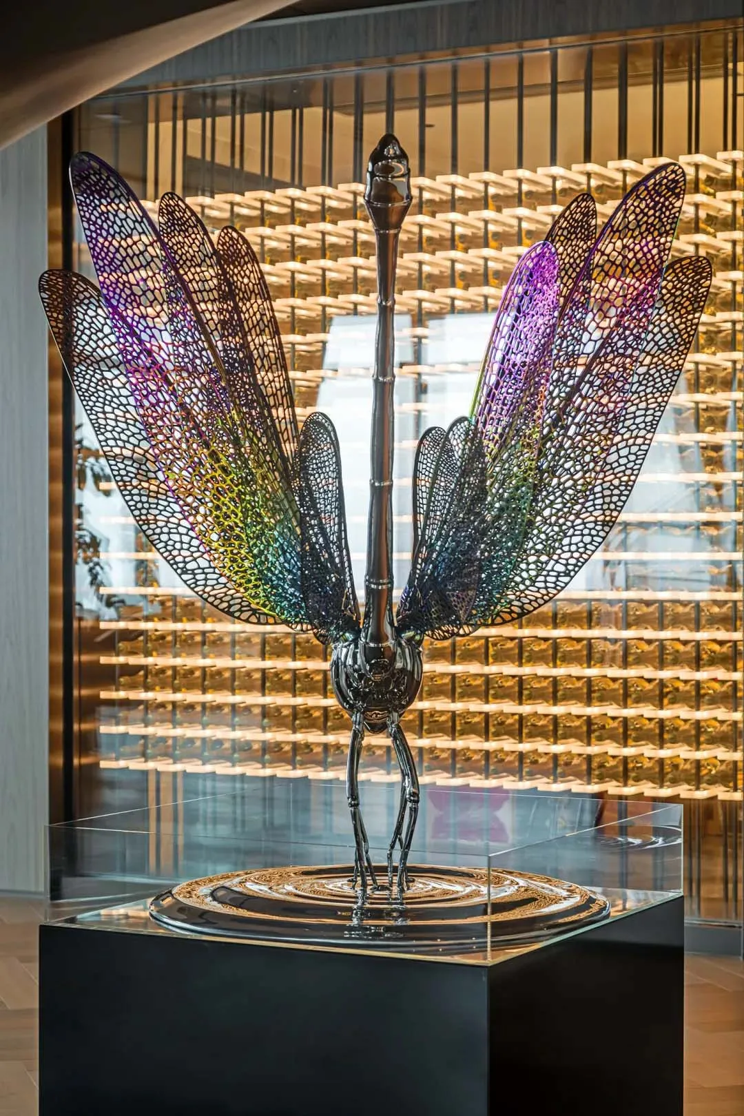 A large, metallic dragonfly sculpture with multicolored wings on display.