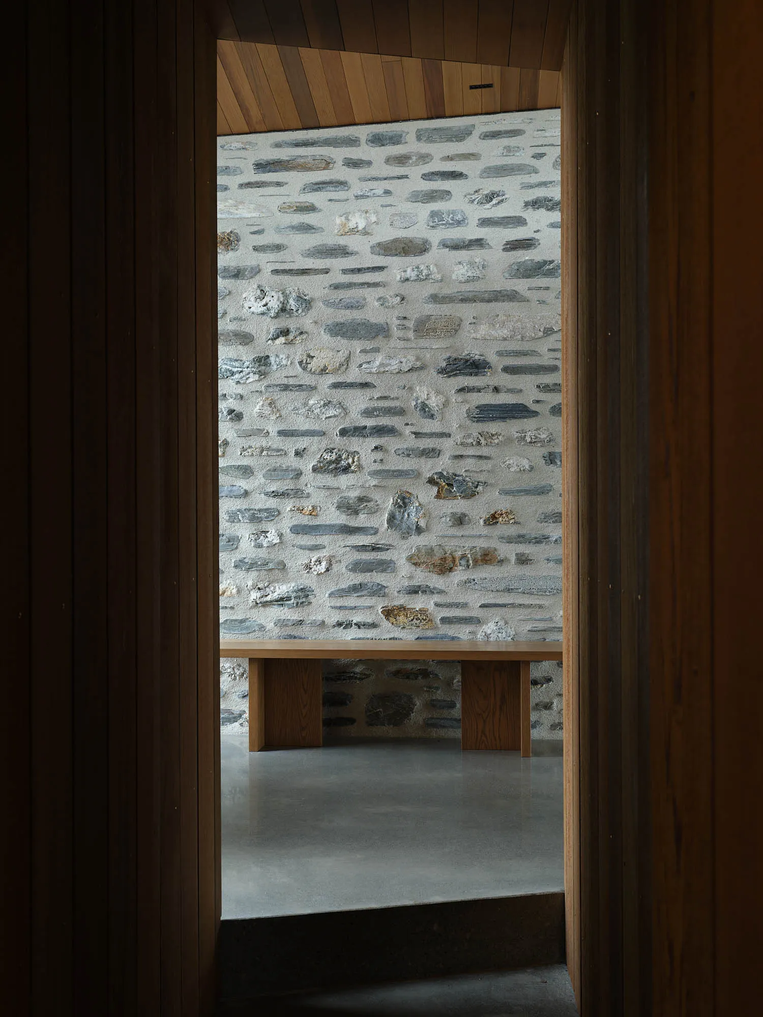 A minimalist interior with concrete walls and wooden furniture.