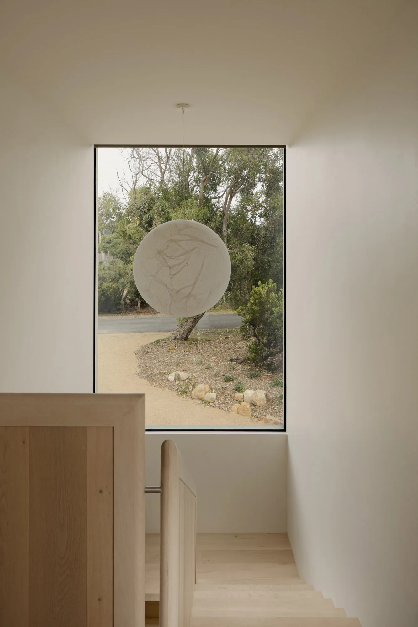 A minimalist window with white lighting and an oak staircase
