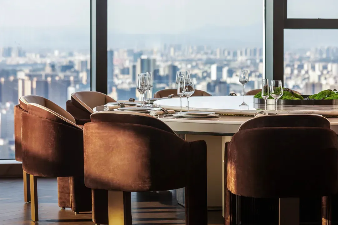 An elegant restaurant space with modern design elements, featuring armchairs upholstered in brown leather and a dining table