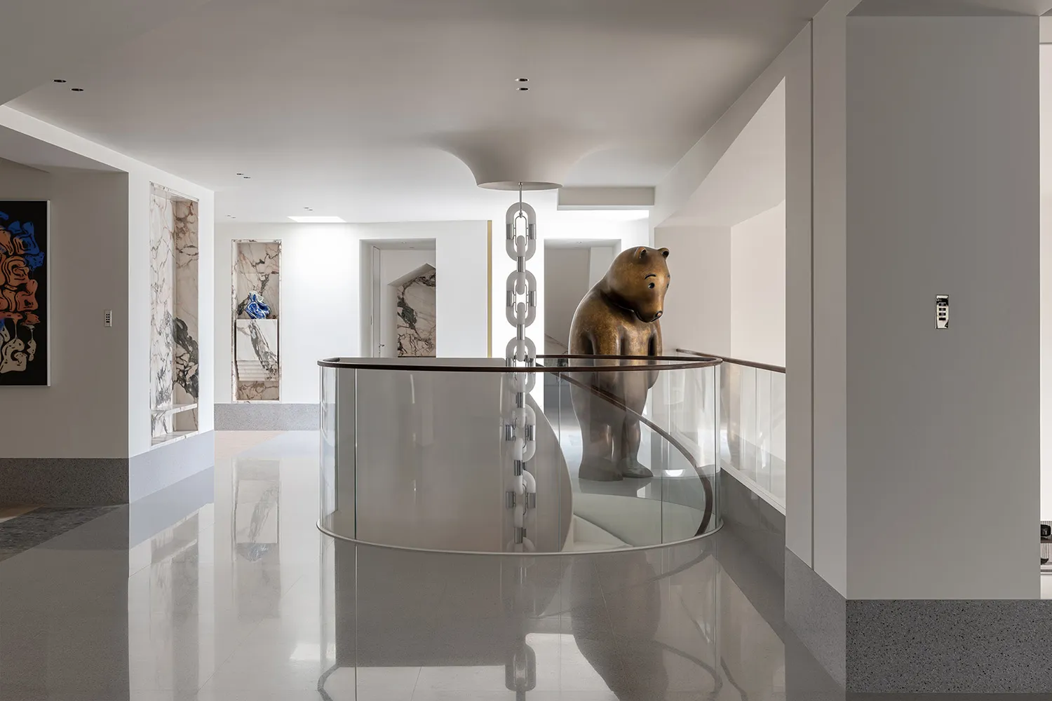 A minimalist interior space featuring a glass railing with a bronze bear statue.