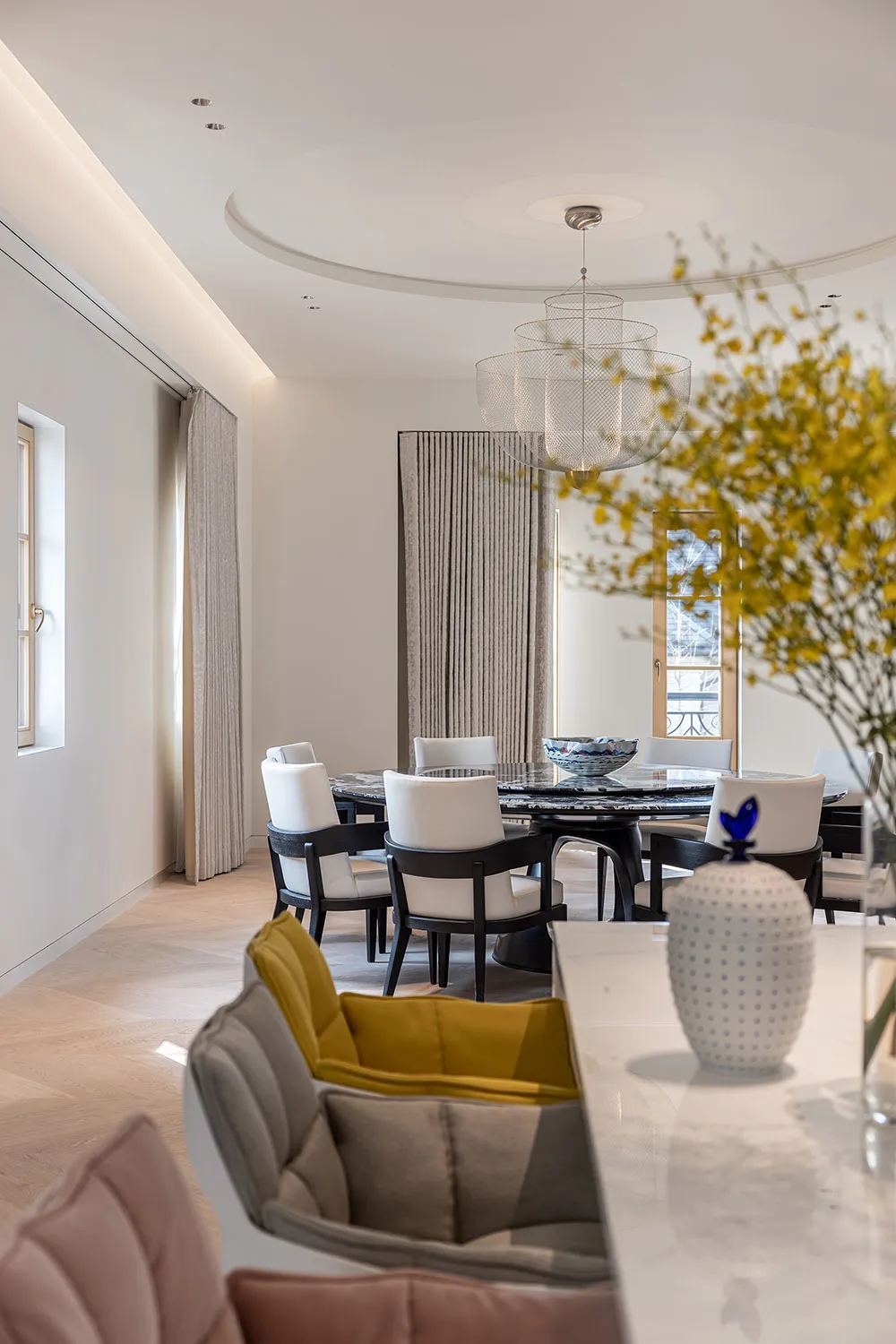 Modern dining room with marble table and chairs, featuring elegant chandeliers