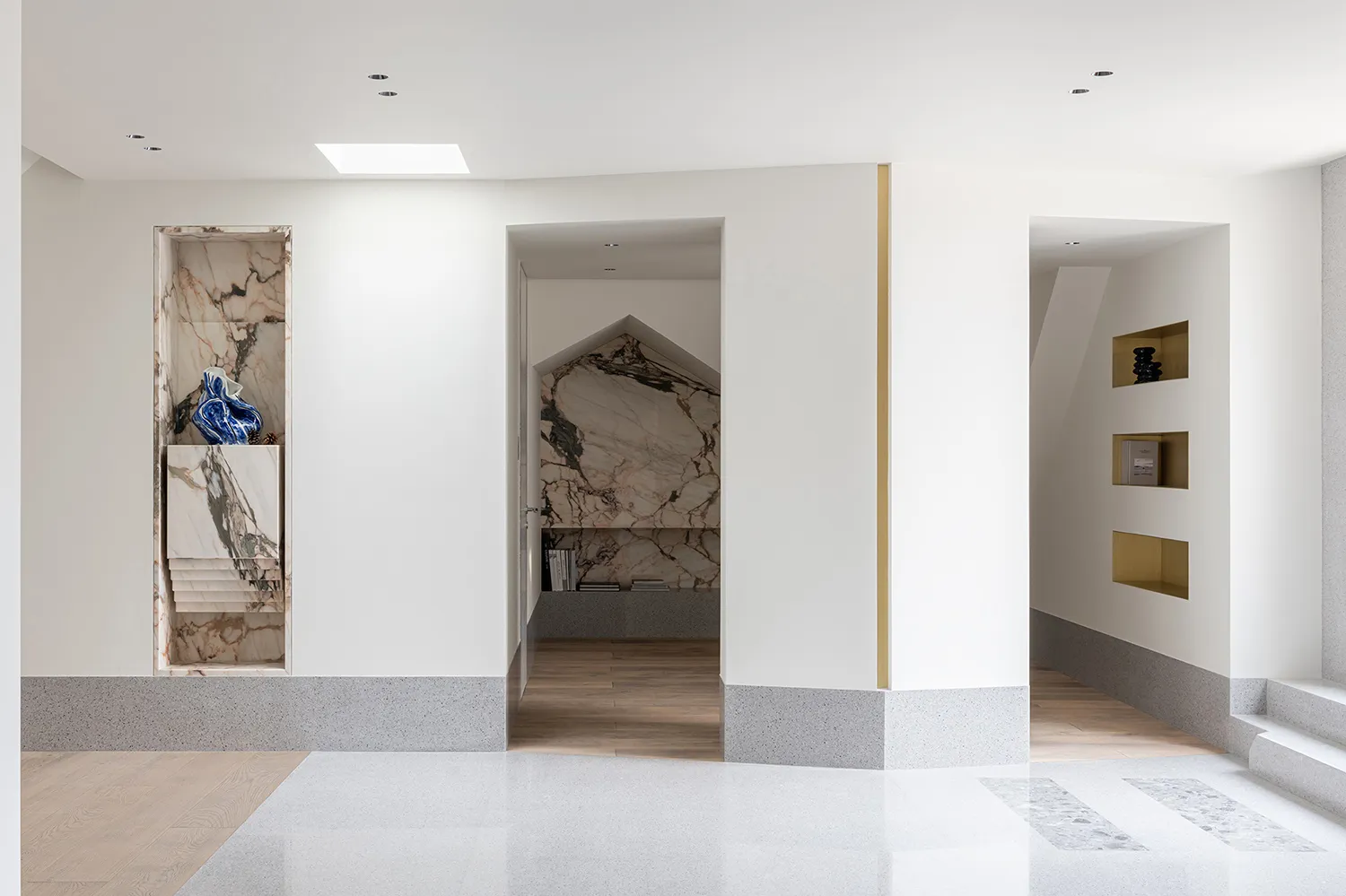 A modern interior featuring marble and concrete elements in an entryway setting.