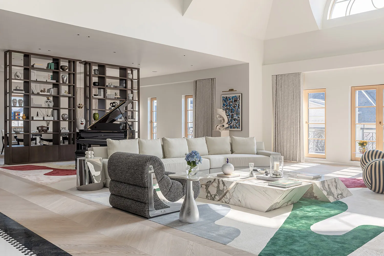 Modern living room with marble coffee table, wooden flooring, and glass bookshelves.