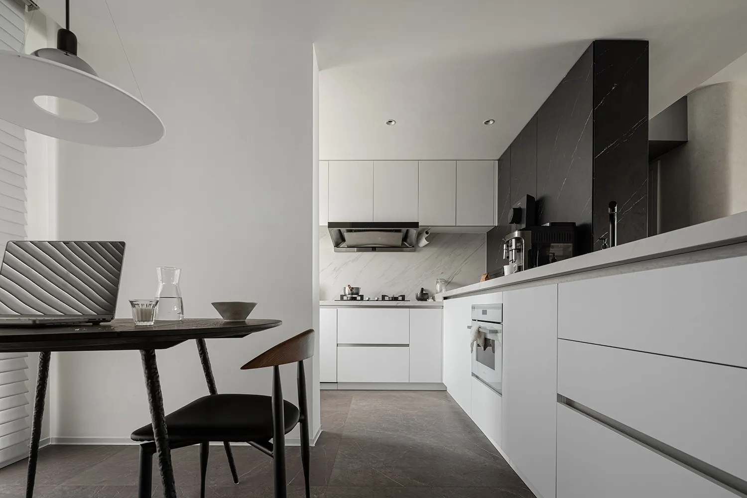A modern kitchen with minimalist design, featuring marble countertops and stainless steel appliances.