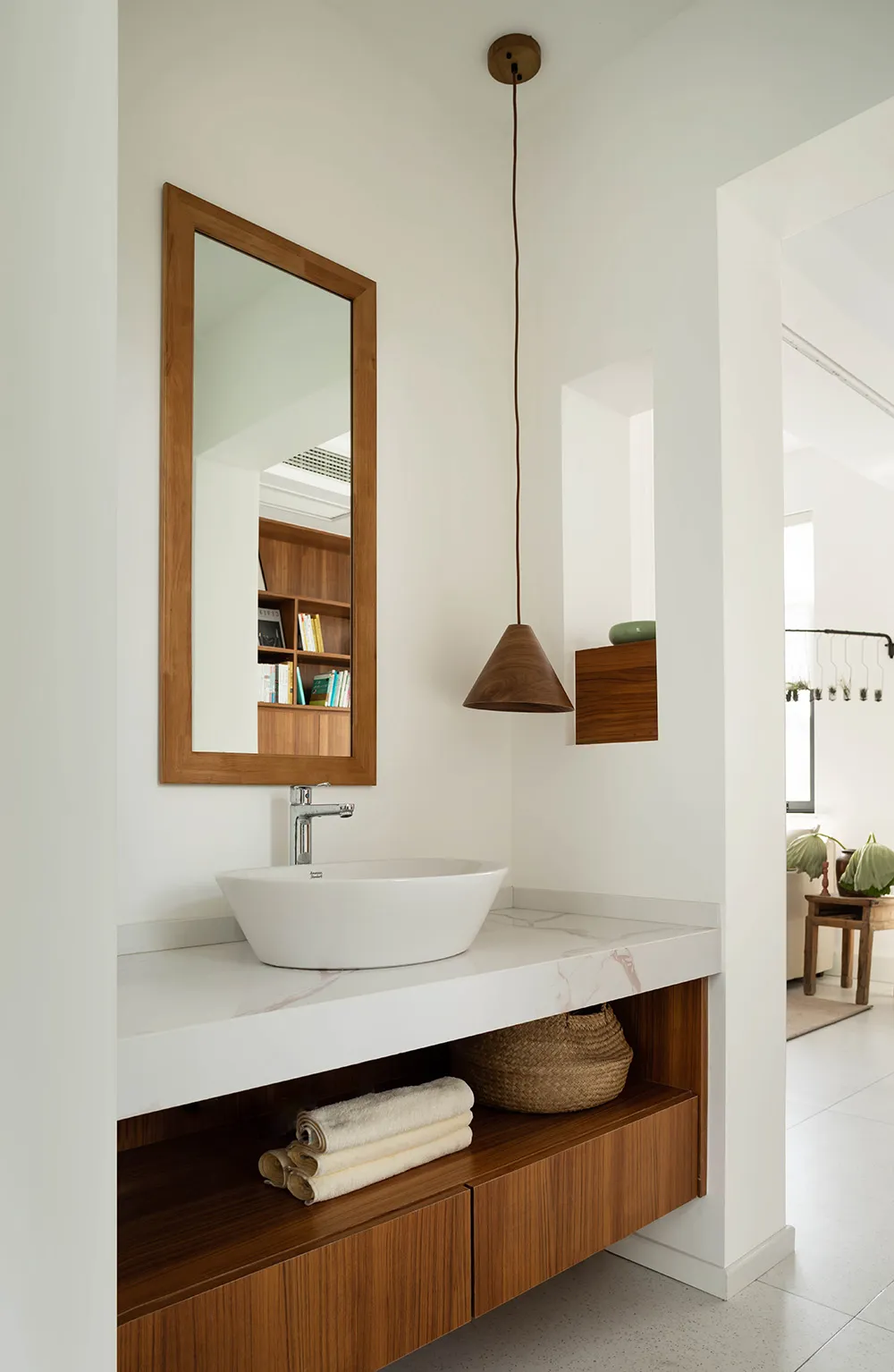 Modern minimalist bathroom with a white marble sink, wooden shelves, and a wooden pendant light.