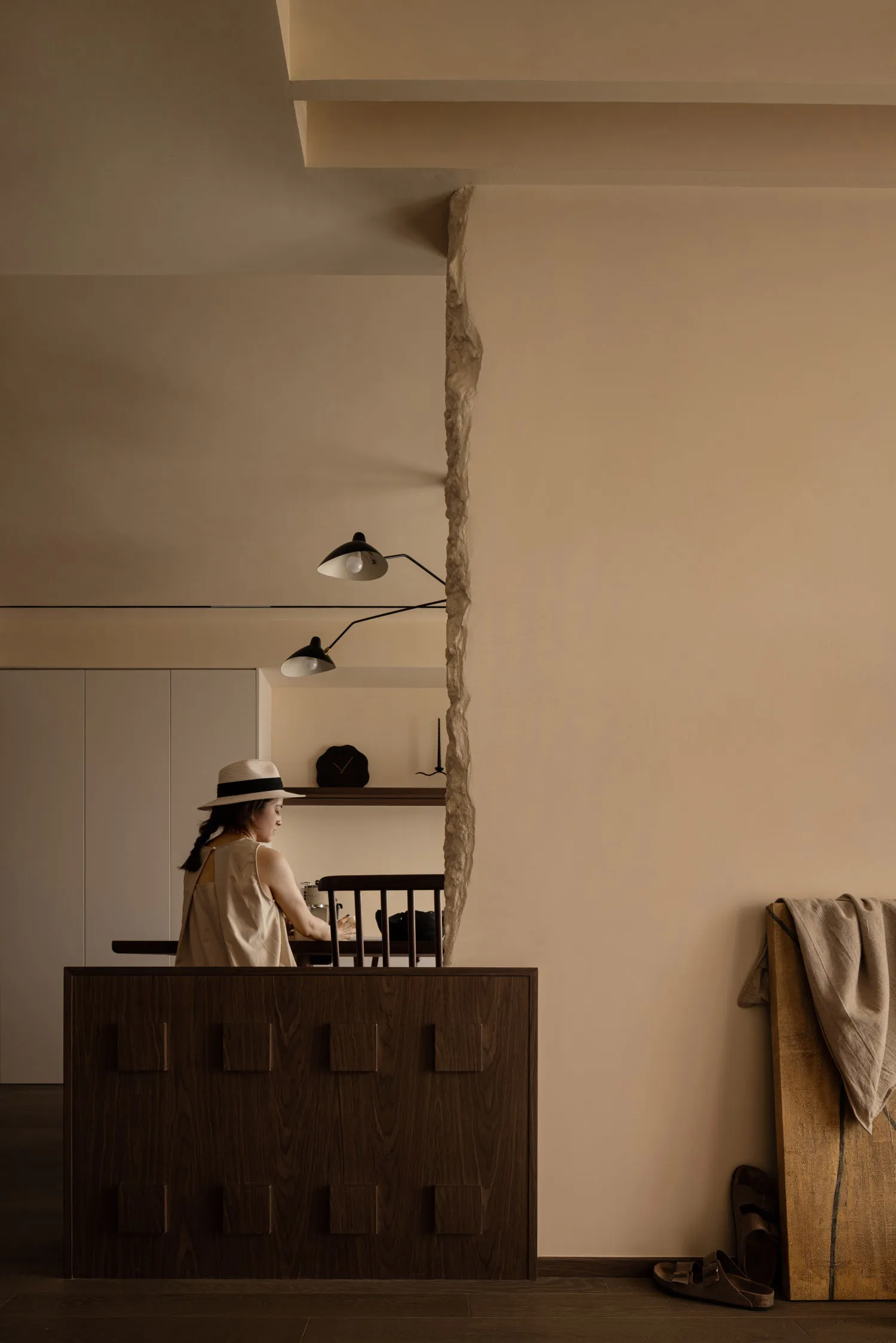 A minimalist kitchen with dark wooden cabinets and a stone wall.