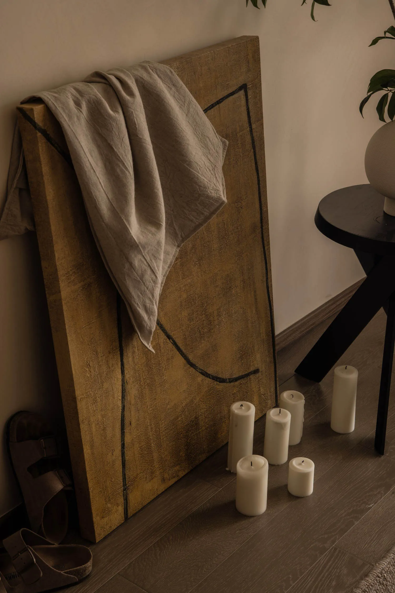 A minimalist living room with candles and a textured wooden panel.