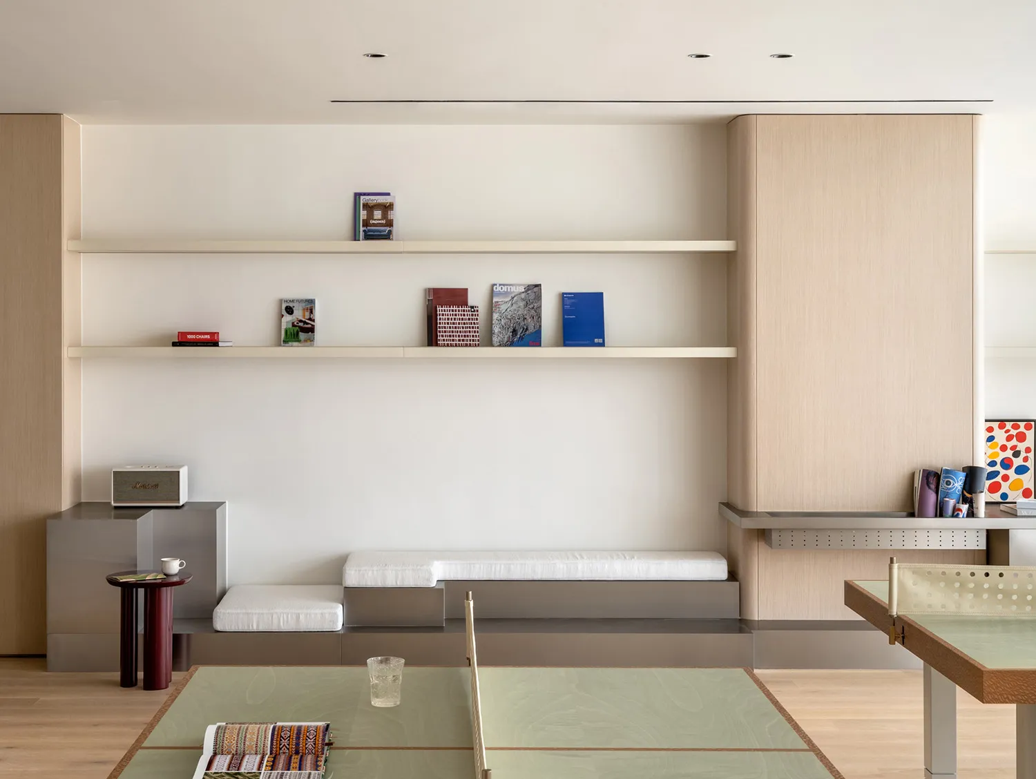 A modern, minimalist living space with light-colored wood flooring, light-colored shelves, and modern furniture.