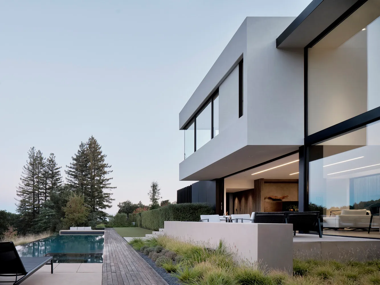A modern house with a concrete exterior features expansive glass windows and a sleek design.