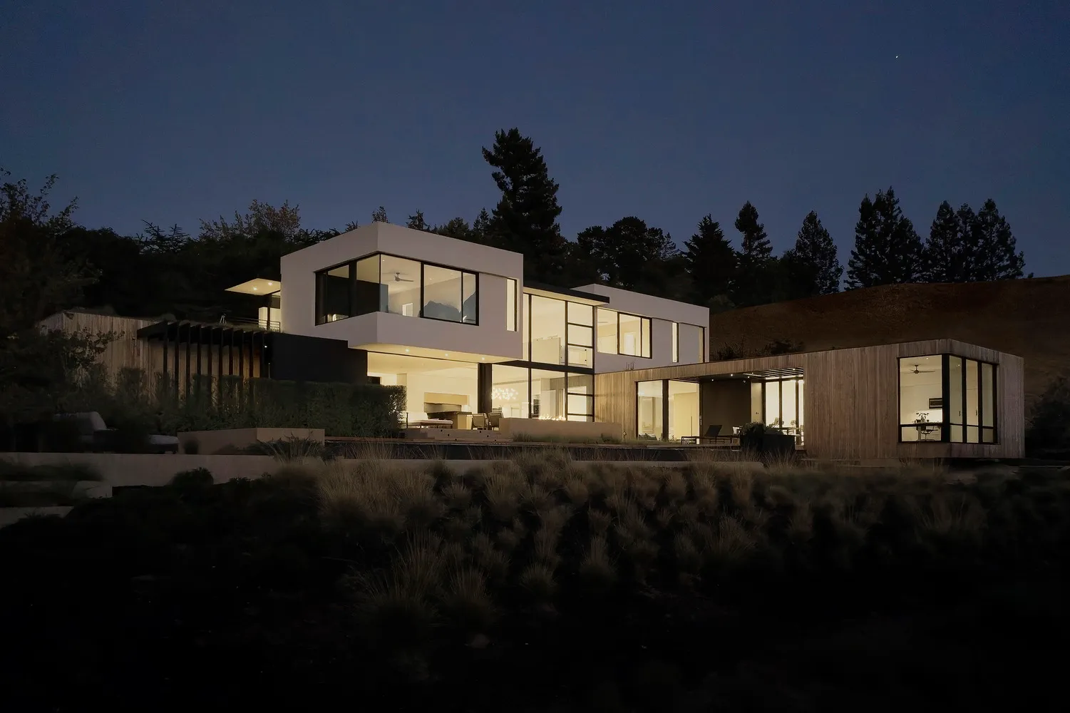 A modern house featuring a contemporary design with wooden accents, glass walls, and concrete structures.