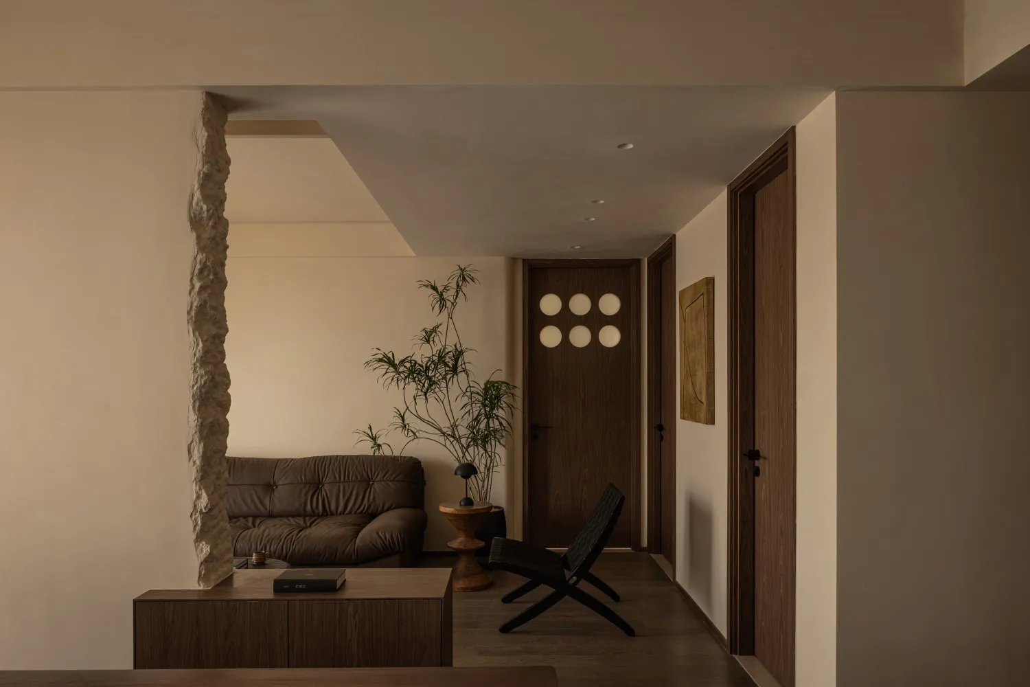Modern minimalist living room with wooden furniture and a stone column.