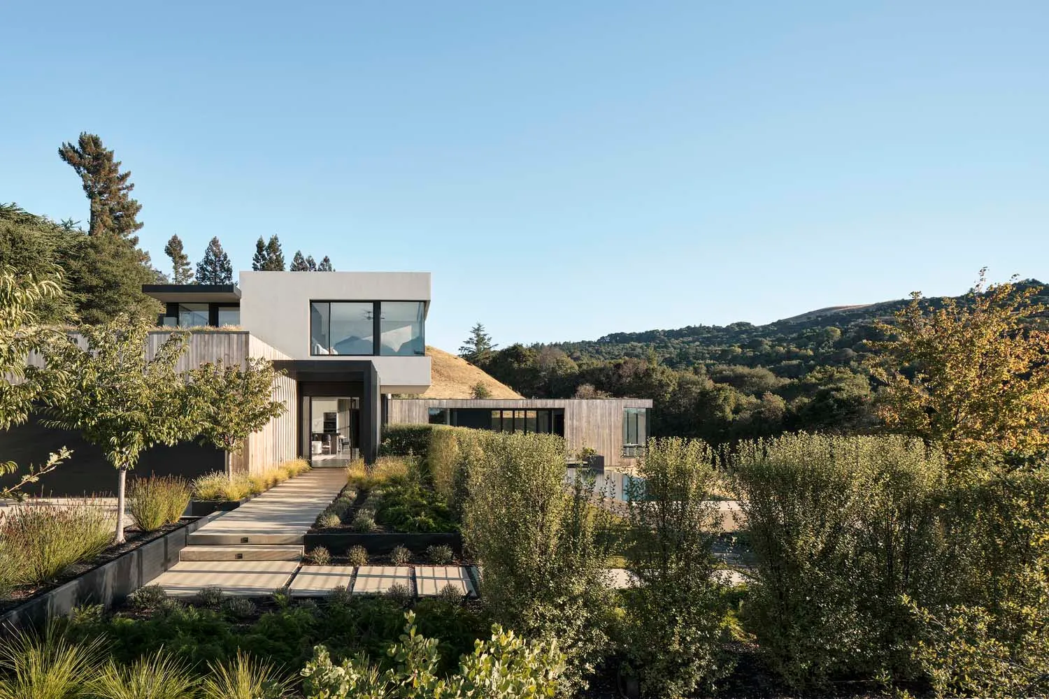 A modern minimalist residential exterior featuring glass windows and concrete materials.