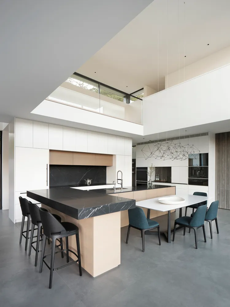 Modern residential kitchen featuring a central island with black marble countertop and metallic accents.