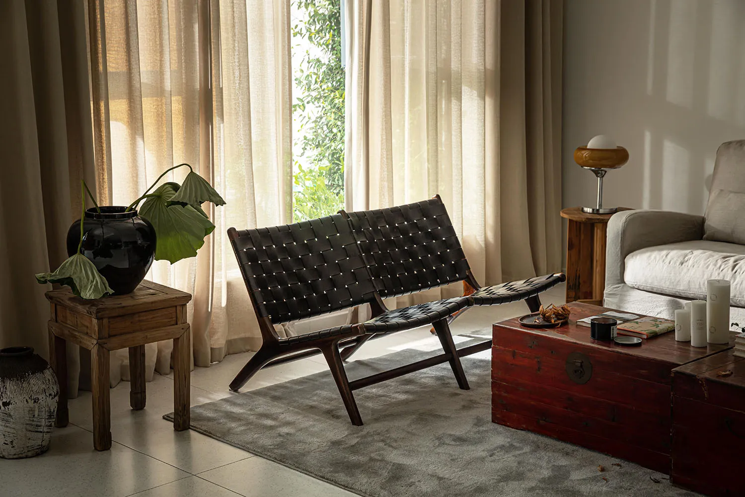 A cozy living room with a woven leather sofa, wooden table, and potted plant.