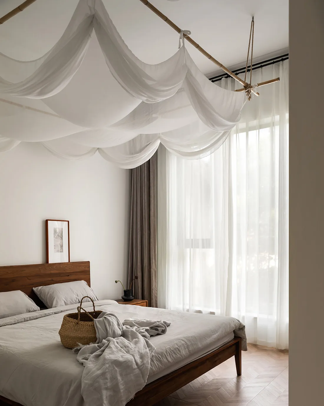 A minimalist bedroom featuring a bed with white curtains and a wooden headboard, minimalistic decor, and a serene atmosphere.