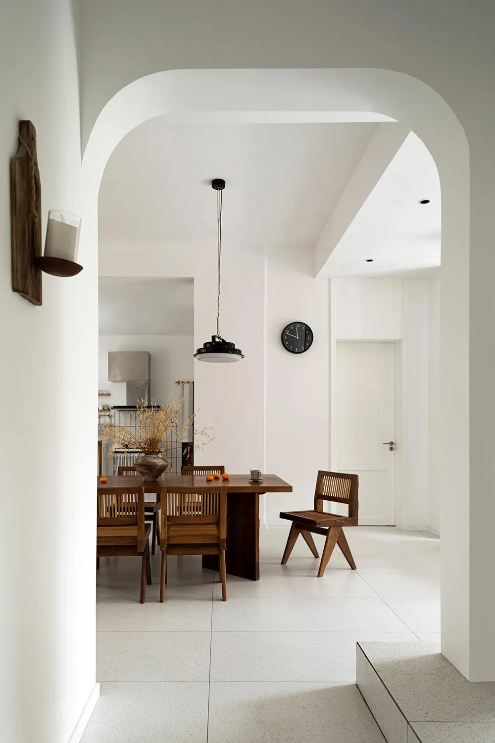 A modern minimalist dining room with wooden furniture and metallic accents.