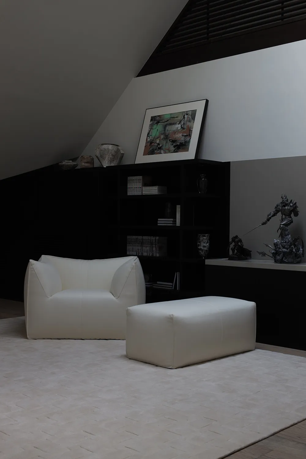A modern living room with a white leather armchair and footstool, black furniture and decor, and minimalist design.