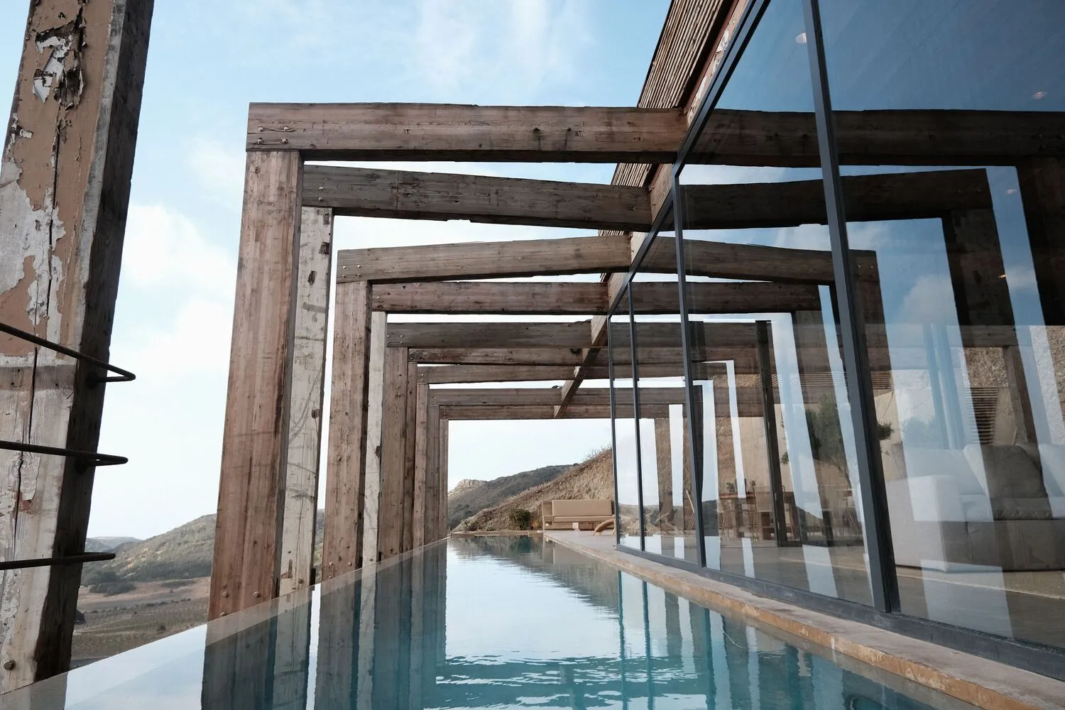 Modern, wood-framed poolside architecture with a glass wall.